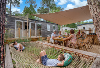 Family relaxing and dining outdoors at Stacaravan Tribu at Flower Camping Au Bois Des Biches in France.