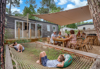 Famiglia che si rilassa e mangia all'aperto allo Stacaravan Tribu al Flower Camping Au Bois Des Biches in Francia.
