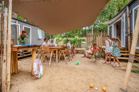 Gezinnen ontspannen buiten bij een Stacaravan Tribu op Flower Camping Au Bois Des Biches, Frankrijk.