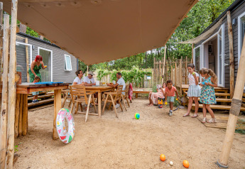 Families relax and play outdoors at a Stacaravan Tribu at Flower Camping Au Bois Des Biches in France.