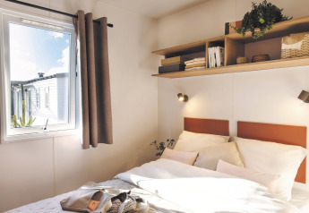 Camera luminosa nello Stacaravan Tribu al Flower Camping Au Bois Des Biches, Francia, con mensola e finestra.