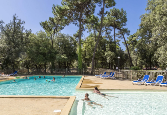 Zwembad met gasten en ligstoelen bij Tente Lodge Confort zonder sanitair op Flower Camping Monplaisir.