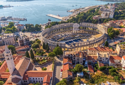 Vista aerea dell'antico anfiteatro romano di Pola, Croazia, circondato da edifici e dal mare Adriatico.