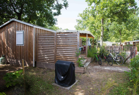 Premium wooden mobile home 33m² with covered terrace and bicycles at Flower Camping La Canadienne in France.