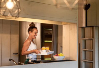 Una donna serve succhi e frutta nella cucina della tenda Safari Cottage al campeggio 't Geuldal, Paesi Bassi.