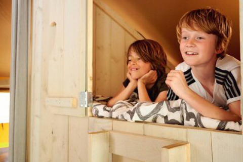 Due bambini sorridenti nel Safari tent Cottage al campeggio 't Geuldal nei Paesi Bassi, visione interna.