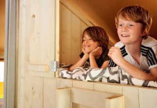 Due bambini sorridenti nel Safari tent Cottage al campeggio 't Geuldal nei Paesi Bassi, visione interna.