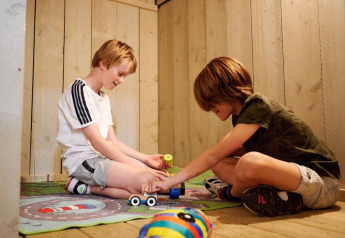 Deux enfants jouent avec des jouets sur un tapis dans une tente safari au camping 't Geuldal aux Pays-Bas.