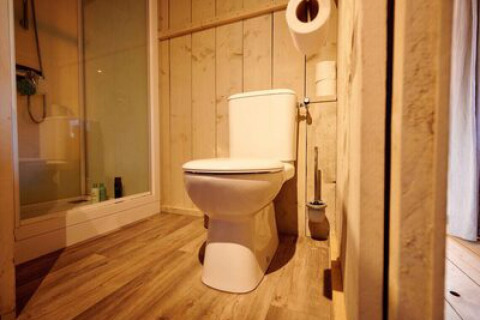 Bagno in tenda safari al campeggio 't Geuldal nei Paesi Bassi, con wc, doccia e pavimento in legno.