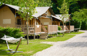 Tenda safari Ranger al campeggio 't Geuldal nei Paesi Bassi con verande in legno e amache tra il verde.