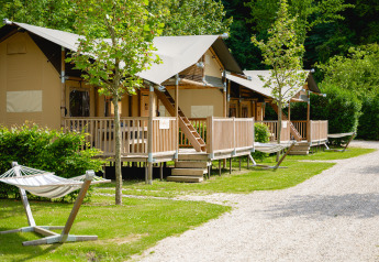 Tente safari Ranger au camping 't Geuldal aux Pays-Bas avec terrasses en bois et hamacs dans un cadre verdoyant.