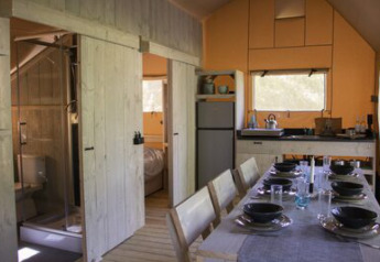 Intérieur de la tente Safari Ranger au camping 't Geuldal, Pays-Bas, avec table à manger et cuisine.