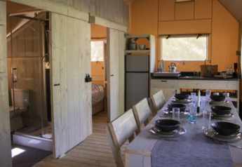 Intérieur de la tente safari « Ranger » au camping 't Geuldal, avec coin repas et cuisine aux Pays-Bas.