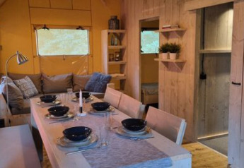 Interior of Safari tent 'Ranger' at Campsite 't Geuldal in the Netherlands, dining area and cozy sofa.