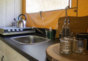 Coin cuisine sous tente Safari « Ranger » au Camping 't Geuldal aux Pays-Bas avec évier et bouilloire.