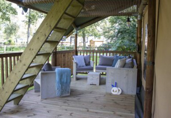 Terrazza in legno con posti a sedere e scala in una tenda safari al campeggio 't Geuldal, Paesi Bassi.