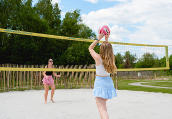 Deux jeunes femmes jouent au beach-volley sur le sable près de la tente Safari «Nomad» au camping 't Geuldal, Pays-Bas.