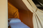 Vue intérieure d’un lit simple avec draps blancs dans une tente Safari Trekking au camping 't Geuldal, Pays-Bas.