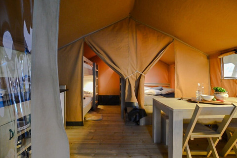 Vue intérieure d'une tente safari compacte au camping 't Geuldal aux Pays-Bas, avec table et lits visibles.