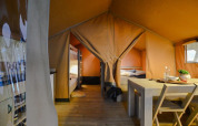 Vista interna di una tenda safari compatta al campeggio 't Geuldal nei Paesi Bassi con tavolo e letti.