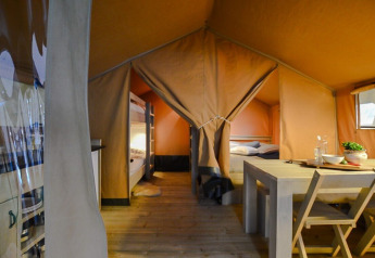 Vue intérieure d'une tente safari compacte au camping 't Geuldal aux Pays-Bas, avec table et lits visibles.