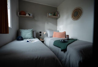 Twee eenpersoonsbedden in een modern ingerichte kamer van Limburg Lodge op Kampeerterrein 't Geuldal.