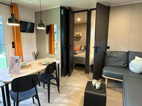 Moderne woonkamer in Limburg Lodge op Camping 't Geuldal, Nederland, met eethoek en bankstel.