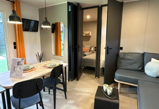 Moderne woonkamer in Limburg Lodge op Camping 't Geuldal, Nederland, met eethoek en bankstel.