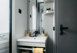 Modern compacte badkamer met gele accenten in Limburg Lodge XL op camping 't Geuldal, Nederland.