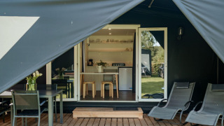 Entrée de la tente safari Coco Sweet avec terrasse en bois, chaises longues et coin cuisine accueillant.