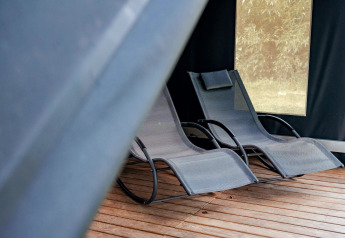 Zwei moderne Liegestühle auf Holzboden im Safari-Zelt Coco Sweet auf Campingplatz 't Geuldal, Niederlande.