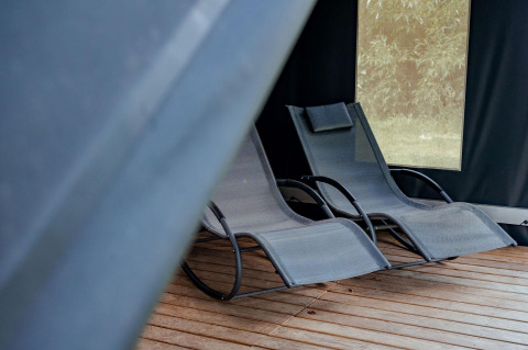 Twee moderne ligstoelen op houten vloer in safaritent Coco Sweet op Camping 't Geuldal, Nederland.