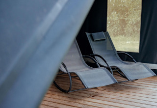 Twee moderne ligstoelen op houten vloer in safaritent Coco Sweet op Camping 't Geuldal, Nederland.