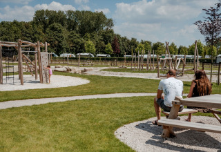 Ouders kijken naar hun kind bij de speeltuin van de Coco Sweet safaritent op Camping 't Geuldal, Nederland.