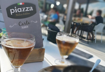 Foto su terrazza di glamping con menù Piazza Italian Kitchen, bicchieri di bevanda e cibo sul tavolo.