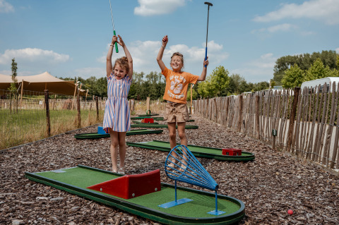 Due bambini felici giocano a minigolf al campeggio 't Geuldal, parco vacanze in Limburgo, Paesi Bassi.