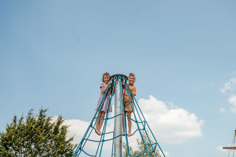 Due bambini scalano una struttura a corde blu al campeggio 't Geuldal in Limburgo, Paesi Bassi.