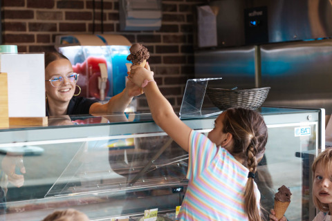 Una dipendente sorridente serve un gelato a una bambina alla gelateria del campeggio 't Geuldal in Limburgo.