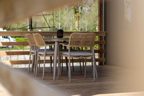 Outdoor dining area with four chairs and a table on a wooden deck at Campsite 't Geuldal, Limburg, Netherlands.