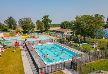 Foto di una piscina all'aperto, famiglie e area giochi su prato presso un alloggio glamping.