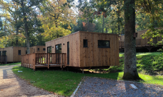 Houten huisjes in het groen bij Hameau de la Semois, een vakantiepark in Belgisch Luxemburg, België.