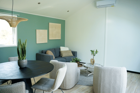 Moderne living in Heuvelrug Cottage met groene muur, zachte zetels en kamerplanten, Nederland.