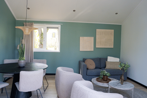 Moderne stue i Heuvelrug Cottage med grå sofa, runde borde, planter og spisebord på De Thijmse Berg.