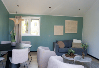 Salón moderno en Heuvelrug Cottage con sofá gris, mesas redondas, plantas y mesa de comedor en De Thijmse Berg.
