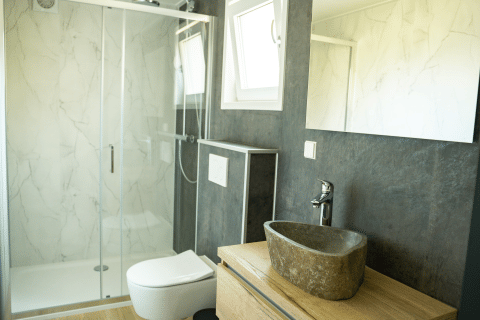 Moderne badkamer met stenen wastafel en glazen douche in Heuvelrug Cottage, De Thijmse Berg, Nederland.