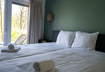 Slaapkamer in Heuvelrug Cottage, De Thijmse Berg, Nederland met schone handdoeken en uitzicht op terras.