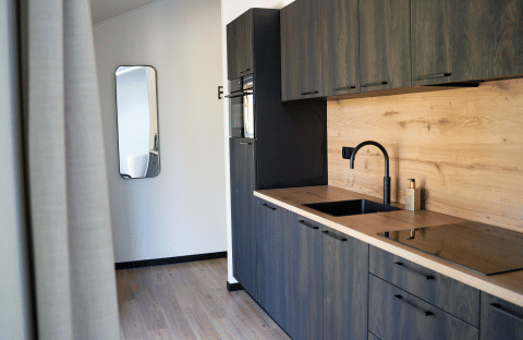 Moderne keuken met donkere kasten en houten blad in Heuvelrug Cottage bij De Thijmse Berg, Nederland.