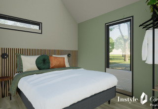 Moderne soveværelse med grøn væg, stor seng og minimalistisk indretning i Cosy Lodge på Camping Si-Es-An.