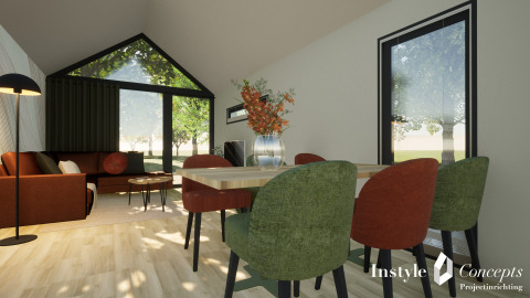 Moderne og hyggelig lodge-stue med store vinduer, grønne og røde stole ved spisebord på Camping Si-Es-An.