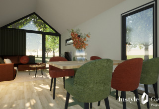 Moderne og hyggelig lodge-stue med store vinduer, grønne og røde stole ved spisebord på Camping Si-Es-An.